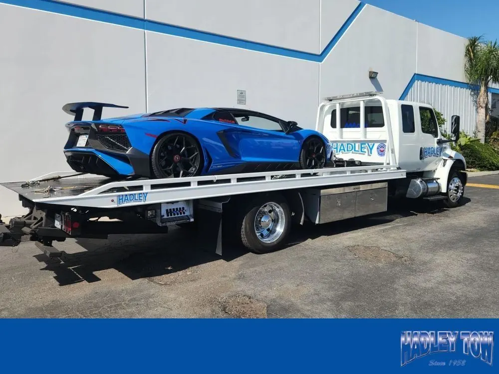 Blue Lamborghini with a black rear wing on a Hadley flatbed