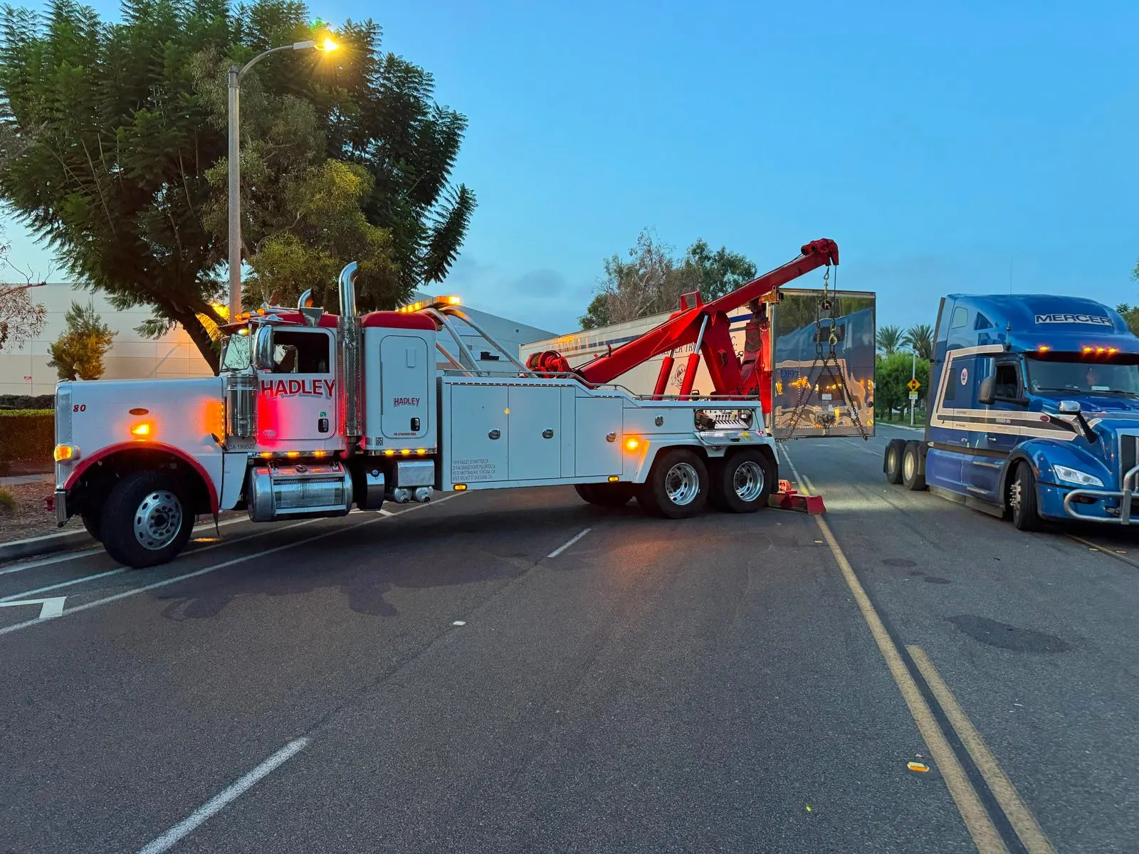 Hadley heavy recovery truck lifting a semi-trailer at dusk