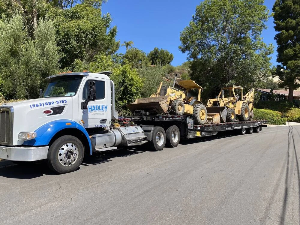 Hadley tractor and trailer transporting two construction machines