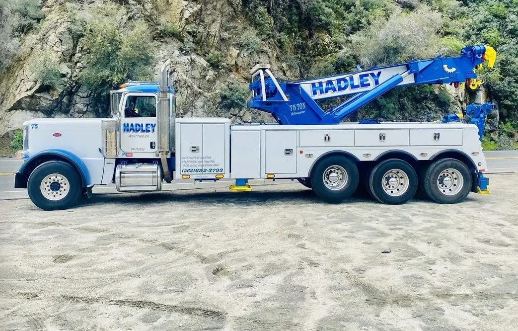 Blue and white Hadley 75-ton rotator truck 75 beside a rocky hillside