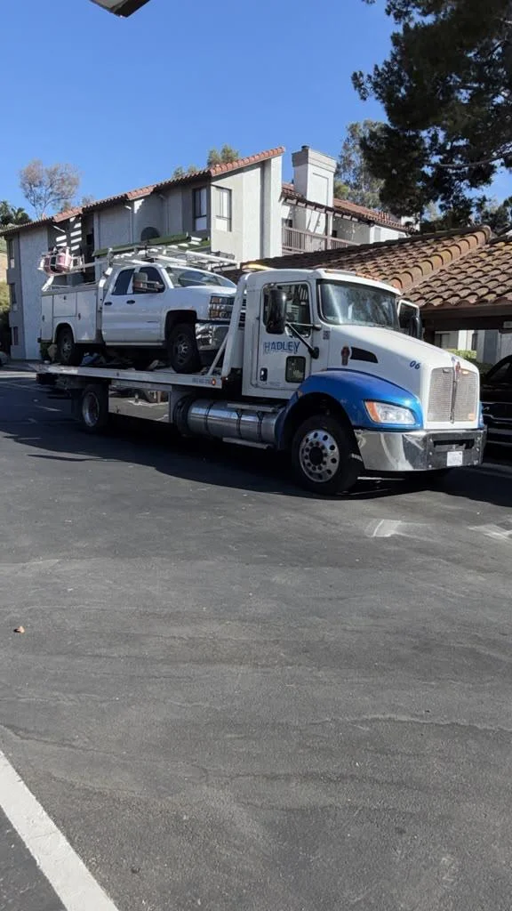 White utility truck carried on a Hadley flatbed