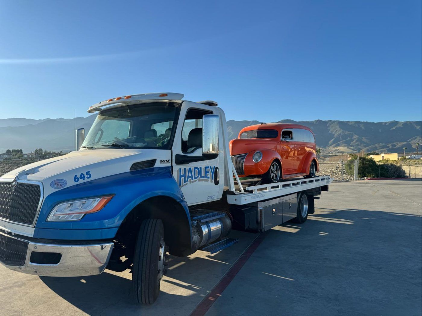 Hadley Tow flatbed transporting a silver Porsche 911 sports car